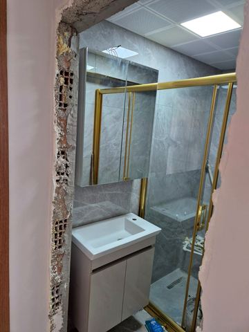 Altın çerçeveli ayna, duş camı ve lavabo