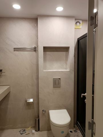 Duş bölmesi, klozet ve raf nişi olan banyo