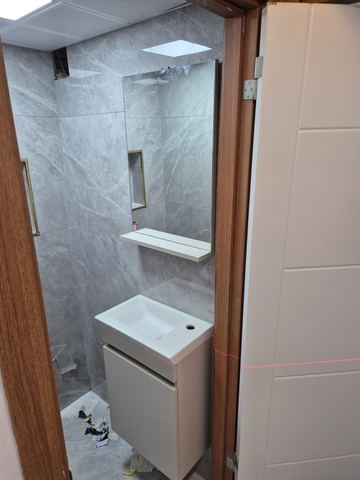 Köşe lavabo ve mermer duvarlı dar banyo