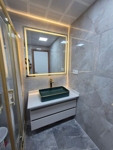 Yeşil taşlı lavabo ve altın çerçeveli ışıklı ayna