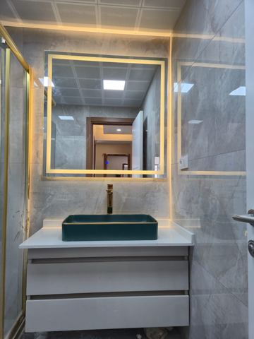 Yeşil taşlı lavabo ve altın çerçeveli ışıklı ayna