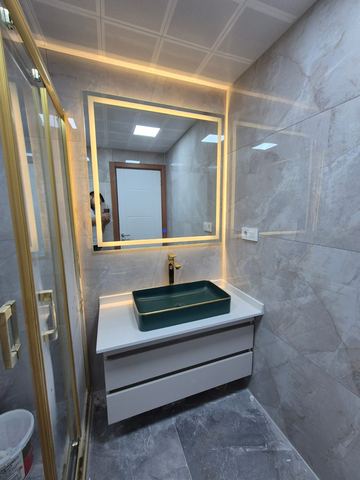 Yeşil taşlı lavabo ve altın çerçeveli ışıklı ayna