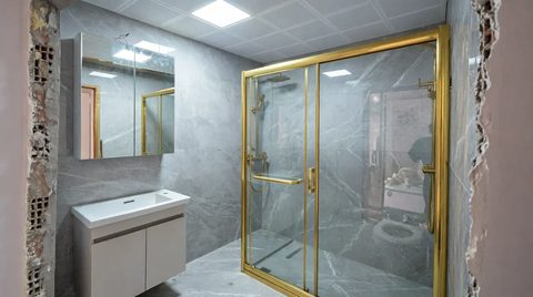 Altın profilli duş kabini ve gri mermer duvar kaplaması