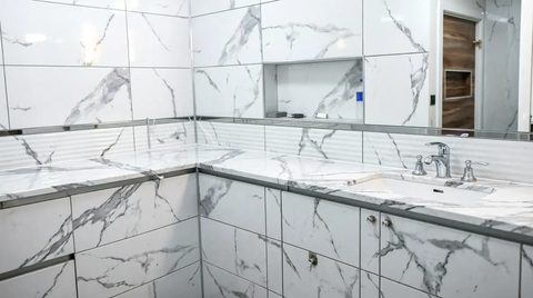 Beyaz mermer kaplamalı geniş banyo tezgahı ve aynası