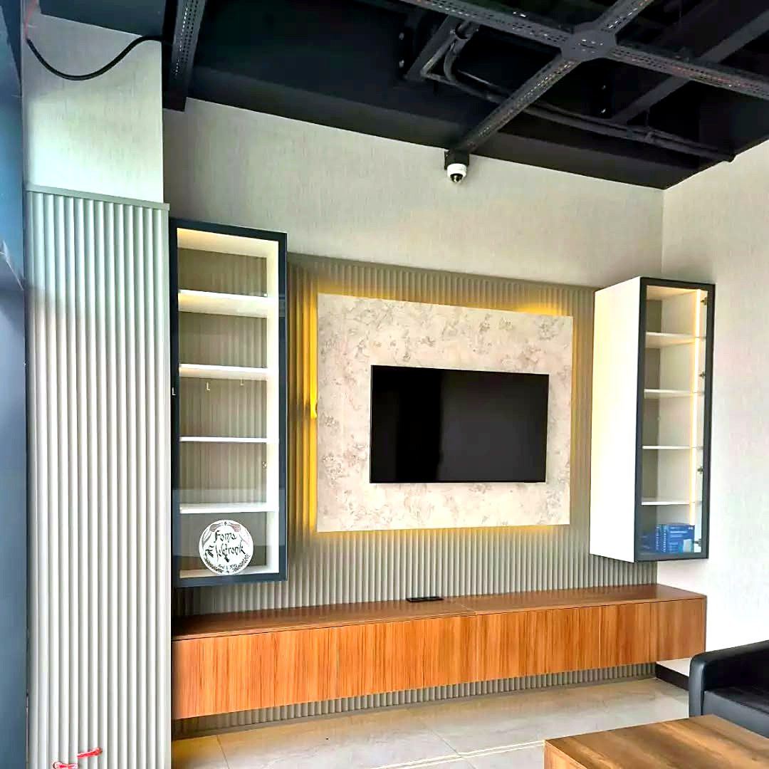Yenilenen salonda taş desenli TV duvarı, gizli LED aydınlatma ve ahşap konsol